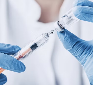 Gloved hands holding a syringe and vaccine vial