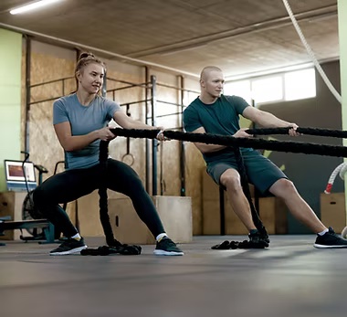 Two people exercising together with training ropes