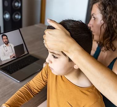 Parent and child having an online consultation with a GP on a laptop
